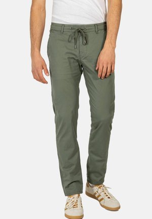 Grüne Baumwollmischungs-Hosen mit elastischem Bund und Kordelzug, mit lockerer Passform und Seitentaschen, kombiniert mit weißen Sneakers.