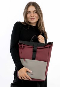Zaino impermeabile rosso e grigio con accenti neri, spallacci regolabili, design roll-top e tasca frontale con zip.