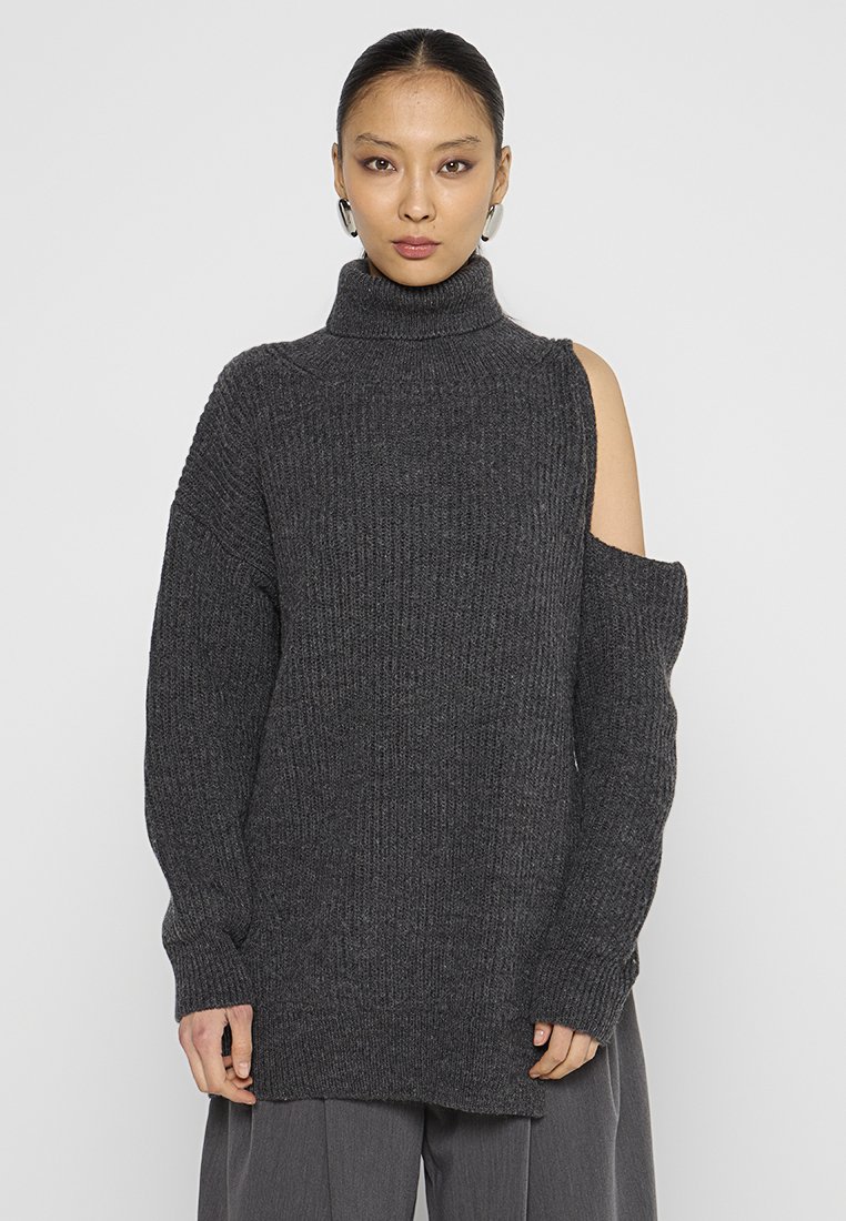 Maglione oversized grigio scuro con texture a costine, collo alto e dettaglio spalle scoperte. Maniche lunghe e vestibilità comoda.