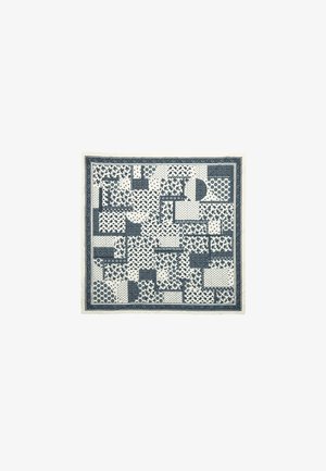 Cotton scarf featuring a patchwork of navy blue patterns on a cream background, with assorted shapes including circles and floral designs.