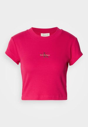 Lyse rosa crop-top med korte ermer, med en liten Calvin Klein-logo i midten. Renslig hvit bakgrunn for fremheving.