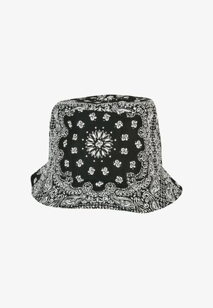 Must kollane suvemüts valge paisley mustriga, millel on lai ja laienev ääreosa ning pehme kangas, pakkudes lõdvestunud, struktureeritud siluetti.