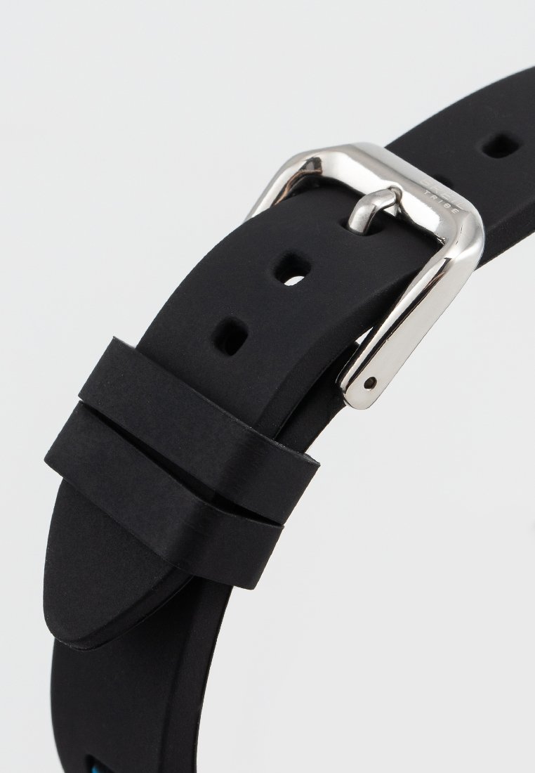 Correa de reloj de silicona negra con una hebilla de plata pulida sujeta a través de un orificio, mostrando dos lazos de correa y una textura suave.