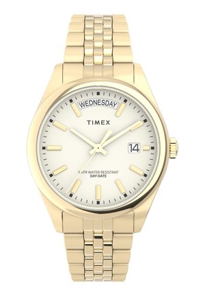 Montre-bracelet Timex en doré avec un cadran blanc, indication du jour et de la date, bracelet en acier inoxydable, et marqueurs et aiguilles luminescents. Résistante à l'eau jusqu'à 5 ATM.
