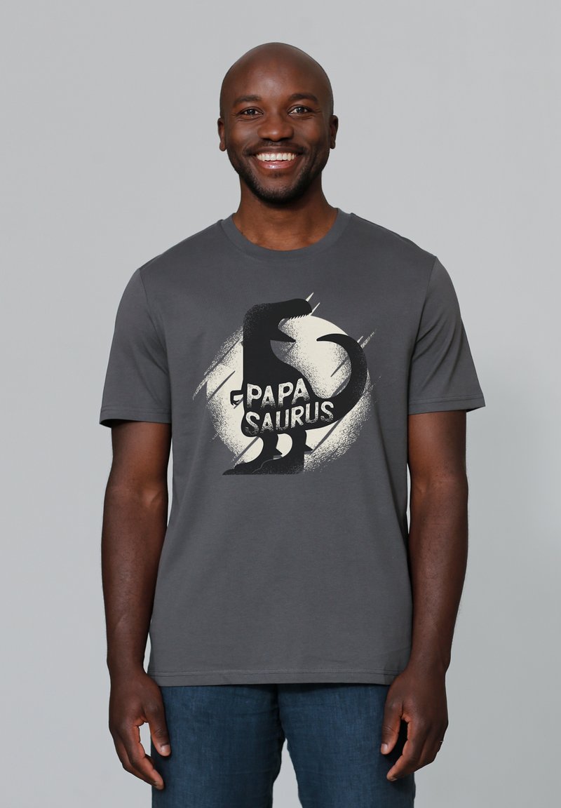 Graues Baumwoll-T-Shirt mit einem schwarzen Dinosaurier-Graphic und dem Text "PAPA SAURUS." Kurze Ärmel und runder Halsausschnitt.