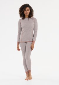Lichtgrijze long-sleeve top en bijpassende getailleerde broek, met textuurstof en contrasterende perzikkleurige accenten langs de naden en manchetten.