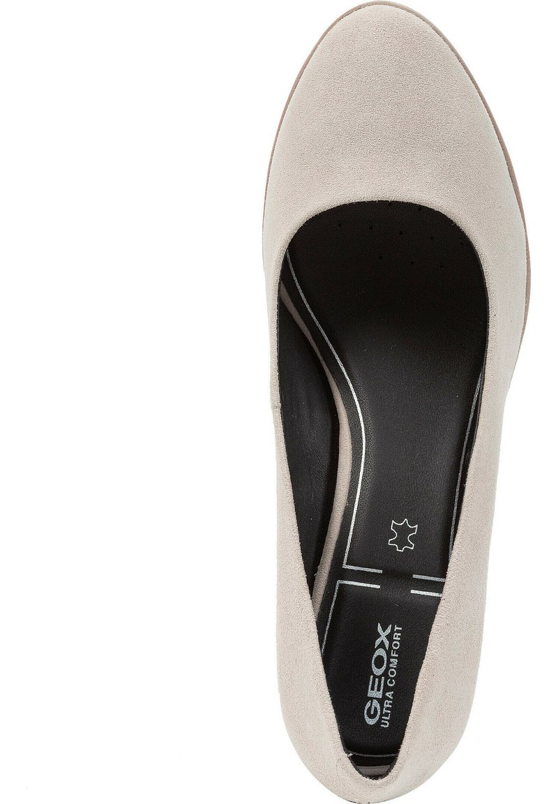 Beige Wildleder-Schuh mit runder Spitze, schwarzem gepolstertem Fußbett und zwei weißen Linien an der Seite als Akzent. Leichtes Design.