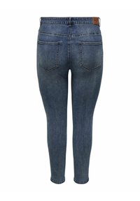 Jeans ajustados de denim azul medio, con cinturilla y dos bolsillos traseros con una sutil textura de desvanecimiento. Parche de cuero de la marca en la parte posterior.
