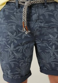 Shorts bleu marine avec un motif de feuilles de palmier, en coton, avec un ourlet roulé et une ceinture en corde rayée avec des embouts à franges.