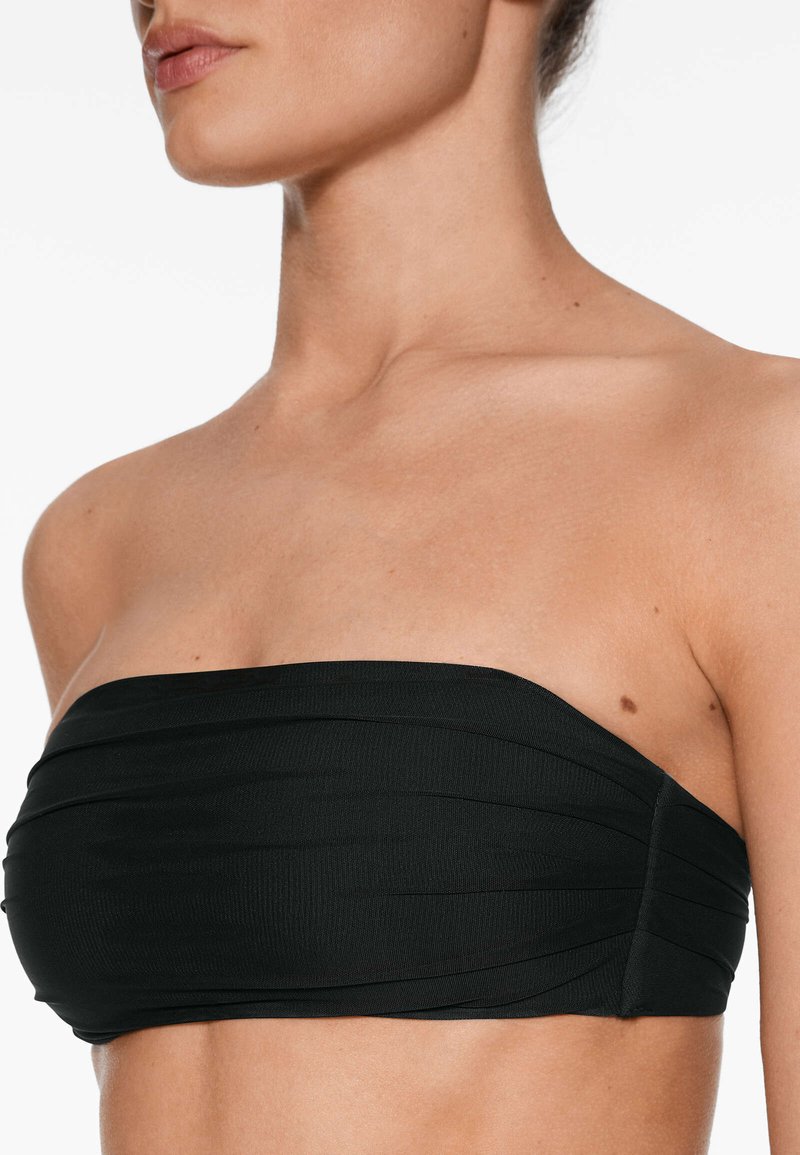 Top bandeau negro sin tirantes con tejido texturizado y diseño plisado, que presenta un acabado suave y sin hardware o acentos visibles.
