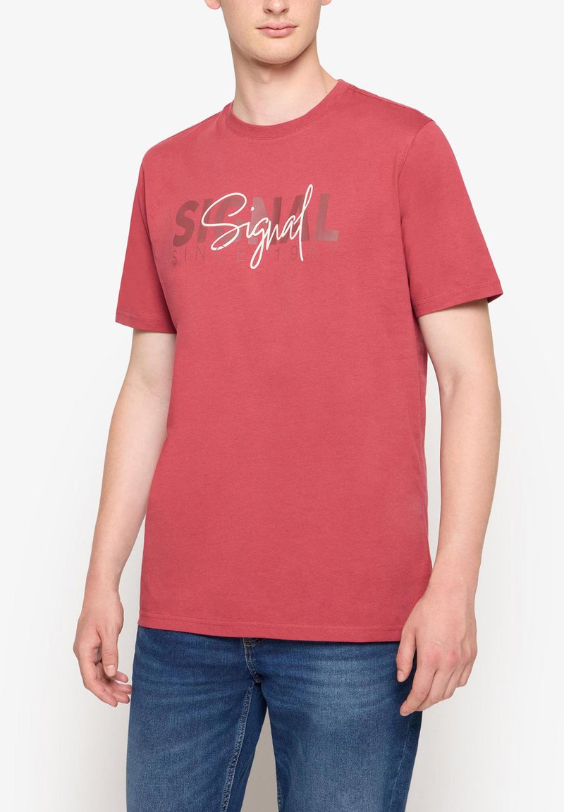 Rød bomulds T-shirt med korte ærmer, der har et grafisk tryk med ordet "Signal" i hvidt mod en mørkere baggrund.