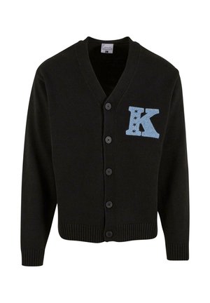 Czarny kardigan z dzianiny, z dekoltem w serek, pięcioma guzikami i haftowaną na jasnoniebiesko literą 'K' z akcentami gwiazdek po lewej stronie klatki piersiowej.