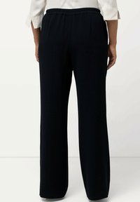 Černé kalhoty s širokým střihem a elastickým pasem, s hladkým povrchem a bez viditelných vzorů či ozdob.