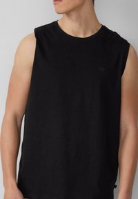 Zwarte mouwloze t-shirt met een ronde hals. Heeft een subtiele QS-logo op de borst. Zacht, lichtgewicht stof met een relaxte pasvorm.