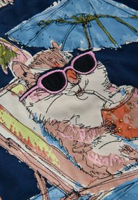 Chat portant des lunettes de soleil roses, se prélassant sur une chaise sous un parasol bleu, entouré de couleurs et motifs sur le thème de la plage.