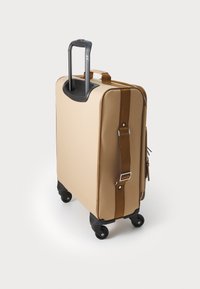 Beige suitcase with a hard exterior, retractable gray handle, brown accent straps, four black wheels, and a zipper closure.
