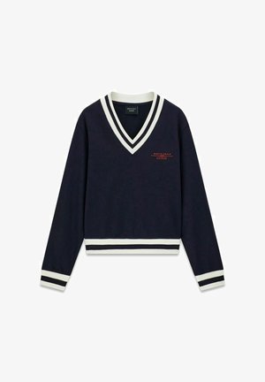 Suéter azul marino con cuello en V y ribetes a rayas blancas y negras en el cuello, puños y dobladillo, con el logo rojo "North Sails Guess" en el pecho.