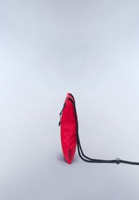 Borsa a pochette in nylon rosso con profilo sottile. Presenta una chiusura con cordoncino nero e una superficie testurizzata. La vista laterale mette in evidenza la sua forma allungata.