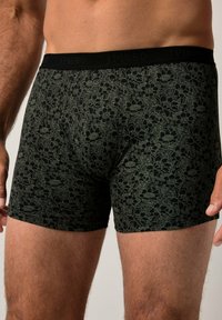 Boxers noirs avec un motif floral en vert foncé. Dotés d'une ceinture douce avec le nom de la marque "JP1880" affiché en évidence.