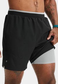 Schwarze Sportshorts mit einem grauen elastischen Bund und innerem Netzfutter. Mit seitlichen Taschen und einem Logo am linken Bein.