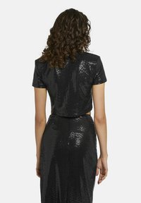 Zwart sequined cropped top met korte mouwen, met een aansluitende pasvorm en een cut-out detail op de rug, die licht reflecteert met een glanzende textuur.