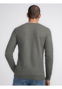 Suéter gris de punto con un patrón texturizado, cuello redondo y puños y dobladillo de canalé. Vista desde la parte de atrás.