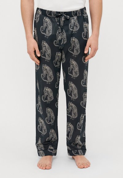 Pantaloni da pigiama neri con un motivo a strisce bianche di tigre ripetuto. Presentano un elastico in vita con coulisse. Tessuto leggero.