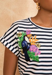 Striped cotton t-shirt with a round neckline, featuring colorful embroidered toucan and floral designs on the front. Short, rolled sleeves.