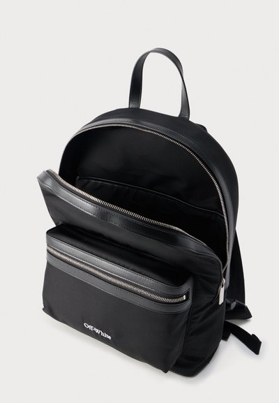 Sac à dos noir Off-White avec compartiment principal ouvert, poche avant zippée, fermetures éclair argentées et poignée supérieure sur fond blanc.