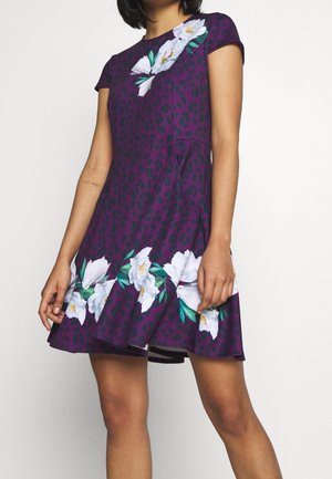 Robe violette avec un motif léopard, manches courtes, accents floraux en blanc, avec une jupe évasée et une texture lisse.