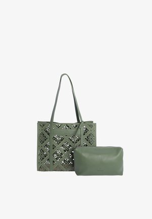 Bolsa de mano verde con patrones florales calados y un estuche verde a juego con cremallera colocado delante sobre un fondo blanco.