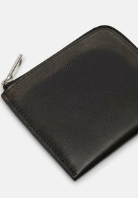 Czarny skórzany portfel na zamek błyskawiczny o teksturowanej powierzchni, ze srebrnymi akcentami i wytłoczonym logo marki. Smukły prostokątny kształt z gładkimi krawędziami.