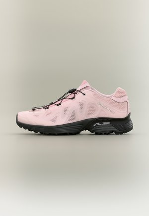 Chaussure de trail Salomon rose clair avec semelle noire et système de laçage rapide, vue de profil sur fond neutre.