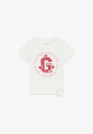 Biała koszulka z krótkim rękawem z czerwoną literą G, koroną, sercem, gwiazdą, grafiką diamentu oraz różowym napisem "Guess Love Since 1981" w kółku, supeł na dole po prawej.