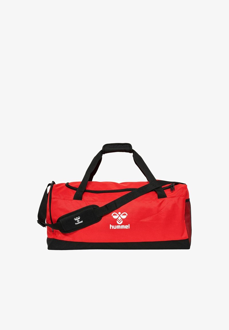 Bolsa de lona roja con acentos negros, hecha de un tejido duradero, que cuenta con asas dobles, una correa de hombro desmontable y un cierre de cremallera.