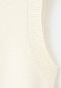 Vestă de pulover crem cu margini striate, realizată dintr-un material moale, texturat. Prezintă un design fără cusături și o croială ușor conică.