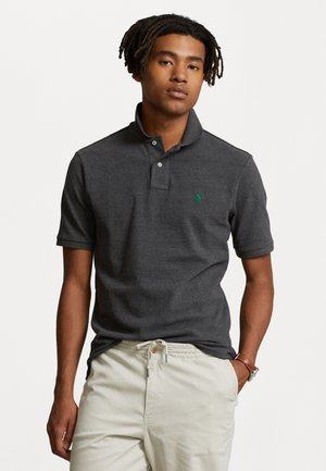 Polo-shirt à manches courtes gris foncé avec un col à deux boutons et un petit logo vert sur la poitrine gauche. Texture douce, design ajusté.