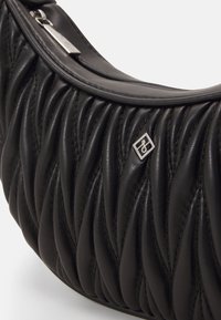 Sac à épaule en cuir noir avec texture matelassée, forme courbée et détail de logo métallique. Dispose d'une fermeture éclair argentée.