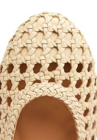 Scarpa in pelle beige intrecciata con un design aperto, caratterizzata da motivi incrociati e bordi lisci. Punta arrotondata con un morbido rivestimento interno.