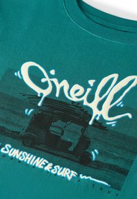 Camiseta de algodón color verde azulado con un gran gráfico en crema que incluye el texto "O'Neill" y "Sunshine & Surf" sobre la silueta de una furgoneta.