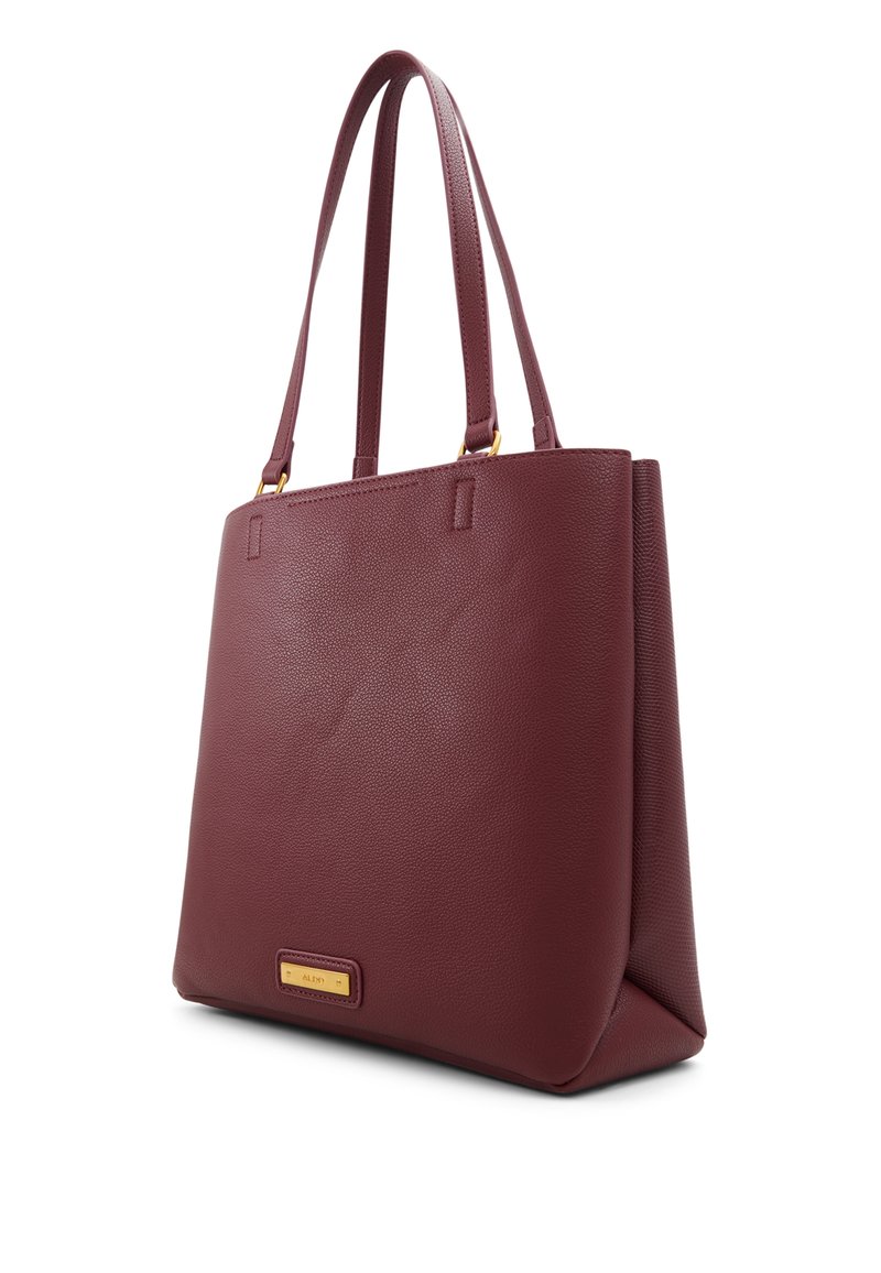 Bolso tote de cuero burdeos con una textura suave, forma estructurada, dos asas largas y un acento en tono dorado del logo en el panel frontal.