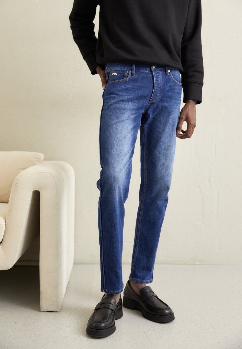 Blå jeans i denim med rak benpassform, blekta detaljer, femficksdesign och kombinerade med svarta loafers på platå.