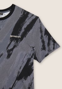 Camiseta de manga corta en gris y negro con un patrón abstracto de pinceladas y el logotipo "FREDDY" en el lado izquierdo del pecho, con un cuello redondo negro.