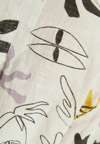 Lichte stof met abstracte vormen van ogen en planten in zwart, paars en geel op een witte achtergrond, met een gestructureerde afwerking.