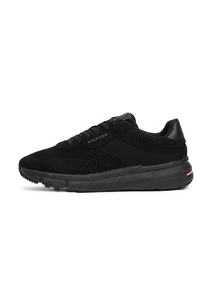 Chaussure de running en maille noire avec un design à lacets, de marque "Hilfiger", et une semelle texturée avec une petite bande rouge, blanche et bleue au talon.