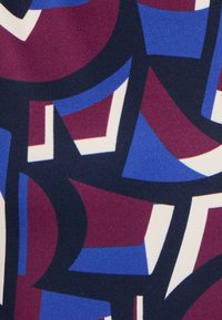 Tessuto stampato con forme astratte in blu scuro, bordeaux e bianco, con una texture liscia e blocchi di colore in contrasto.