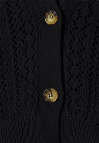Cardigan nero a maglia con un motivo testurizzato, costine verticali e un prominente bottone rotondo in ambra a due fori.
