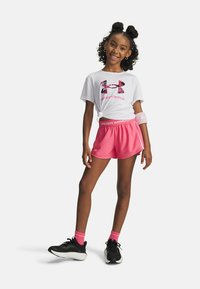 White T-shirt with pink camo logo, pink shorts with "UNDER ARMOUR" waistband, black sneakers, and pink ankle socks.