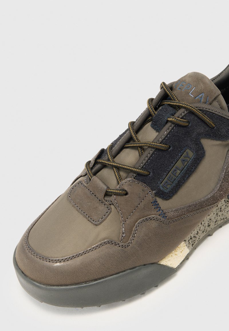 Braune Sneaker aus einer Kombination von glattem Leder und strukturiertem Stoff. Verfügt über tonale Nähte, Schnürdesign und eine gemusterte Gummisohle.