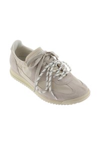 Zapatilla beige y crema con paneles de ante y tela, cordones bicolores atados en lazos y suela de goma texturizada.